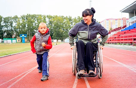 A woman in a wheelchair with a boy on a track.